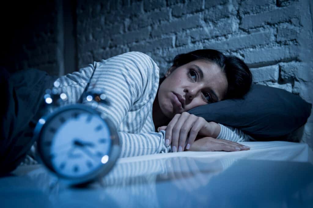 young woman at home bedroom lying in bed late at night trying to sleep suffering insomnia sleeping disorder or scared on nightmares looking sad worried and stressed